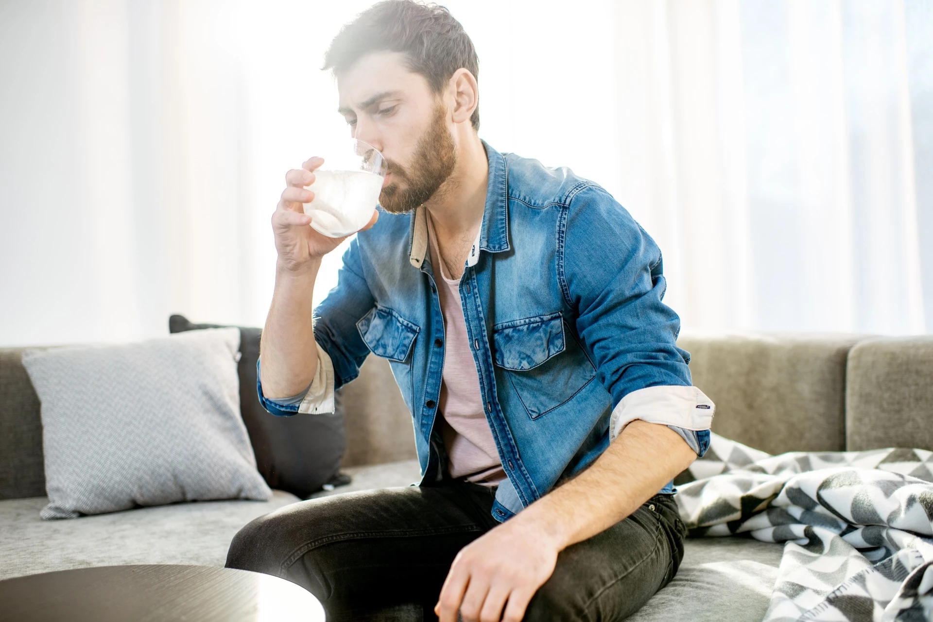 Een zakje O.R.S. poeder voor volwassenen naast een glas water, klaar om opgelost te worden voor gebruik