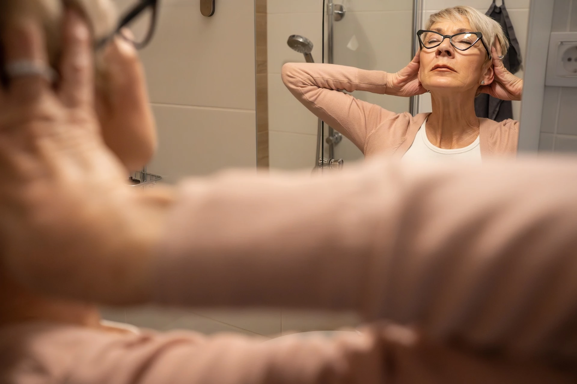 Vrouw in de menopauze ervaart slapeloosheid en kijkt vermoeid in de spiegel